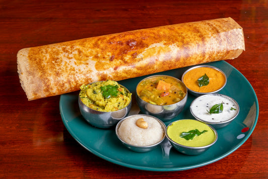 Crispy multigrain atta dosa served with sambar, potato masala and three chutneys on a plate