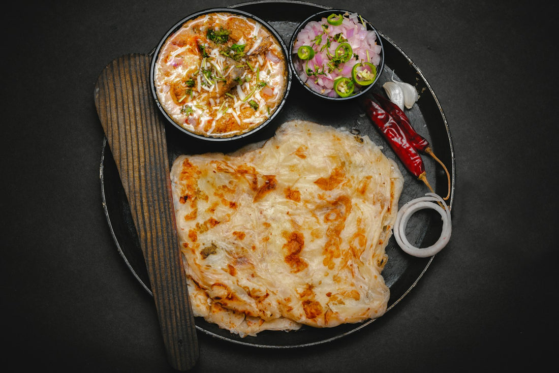 Layered protein atta thepla flatbread served with curry, onion, chili and garlic on a plate